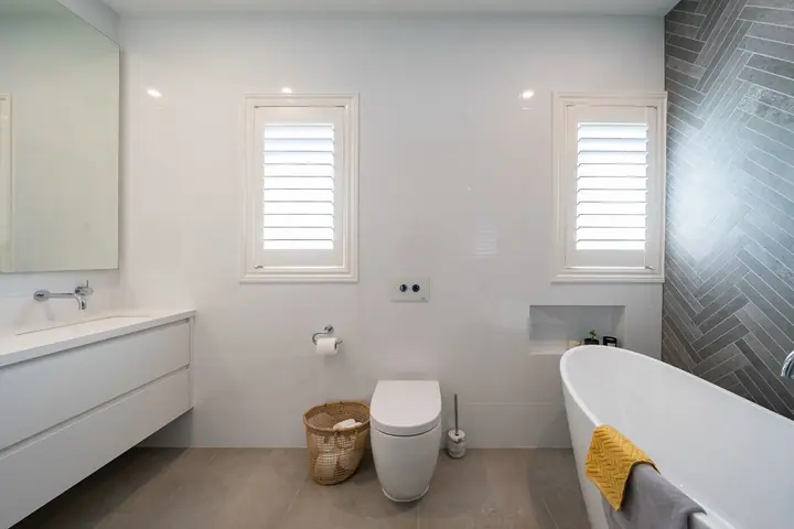Bright bathroom with a vanity, wall-hung toilet and freestanding bath