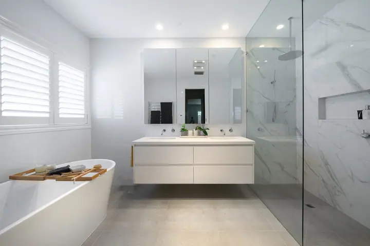 Bathroom with a freestanding bath, double vanity and frameless shower