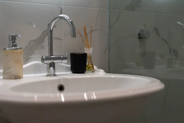 Pedestal basin and chrome mixer against marble-look tiles